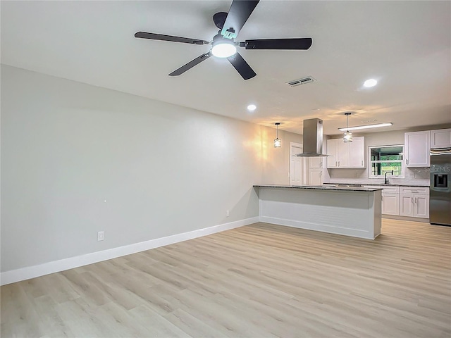 kitchen with white cabinetry, light hardwood / wood-style flooring, kitchen peninsula, pendant lighting, and island exhaust hood