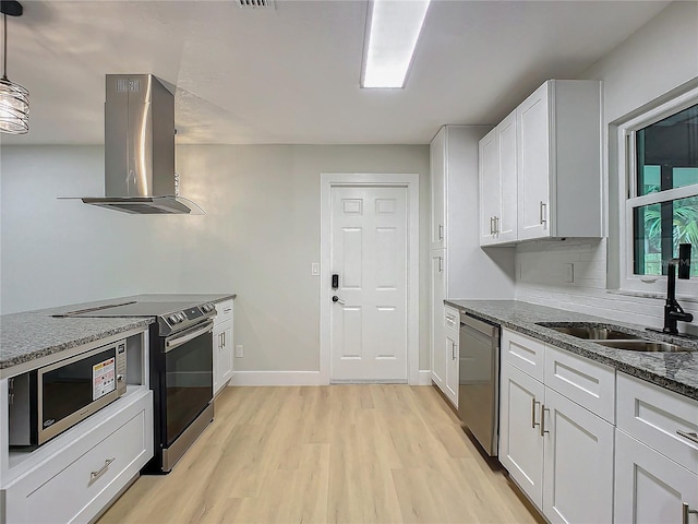 kitchen featuring pendant lighting, appliances with stainless steel finishes, dark stone countertops, island range hood, and white cabinets