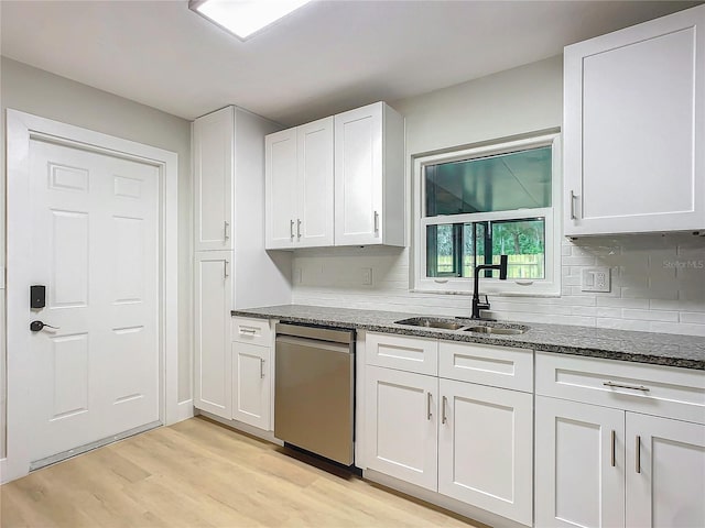 kitchen with sink, white cabinetry, light hardwood / wood-style flooring, dishwasher, and dark stone counters