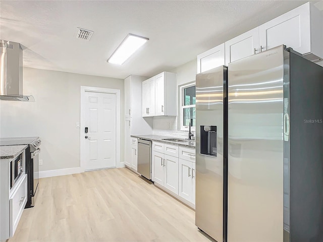 kitchen with sink, stainless steel appliances, wall chimney exhaust hood, and white cabinets