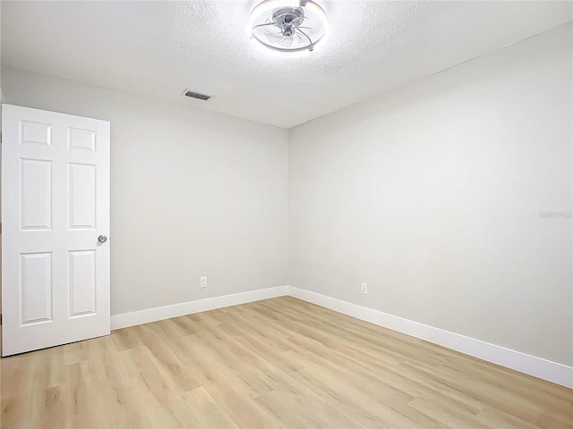 spare room featuring light hardwood / wood-style floors and a textured ceiling