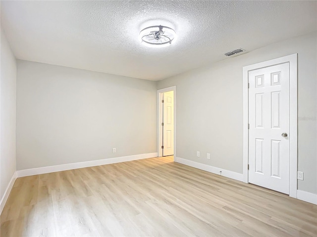 spare room with light hardwood / wood-style flooring and a textured ceiling