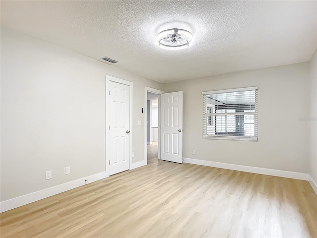 spare room with a textured ceiling and light hardwood / wood-style flooring