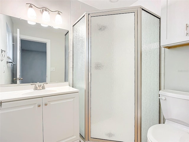 bathroom featuring vanity, toilet, and a shower with shower door