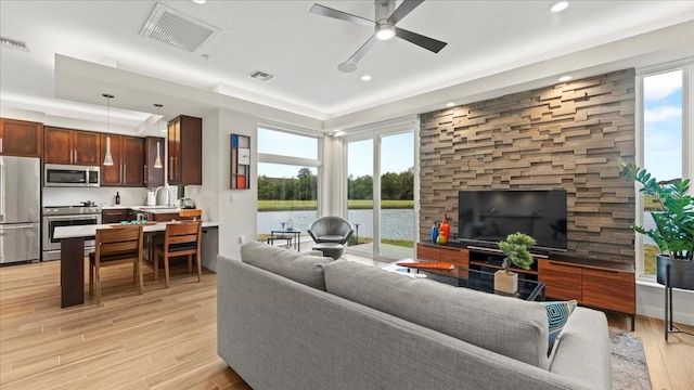 living room with ceiling fan, a healthy amount of sunlight, sink, and light wood-type flooring