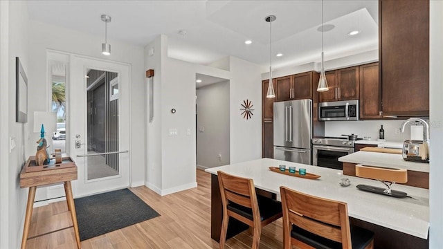 kitchen featuring pendant lighting, sink, light hardwood / wood-style flooring, dark brown cabinets, and stainless steel appliances