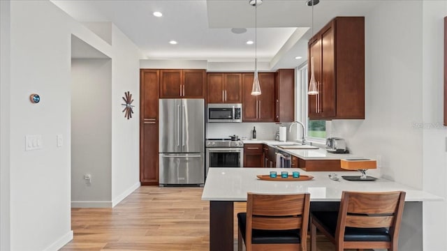 kitchen with a breakfast bar, sink, hanging light fixtures, kitchen peninsula, and stainless steel appliances