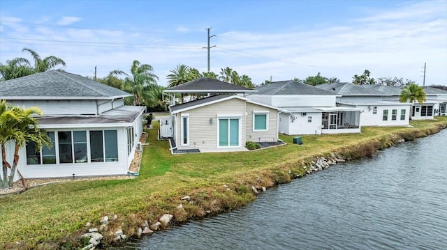 back of house with a water view, a yard, and a sunroom