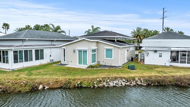 rear view of house featuring a yard, central air condition unit, and a water view