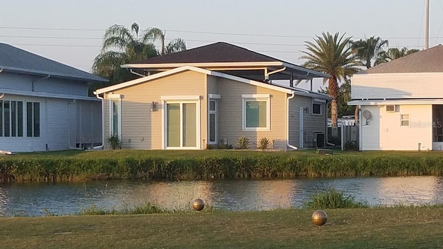 back of property with a yard and a water view