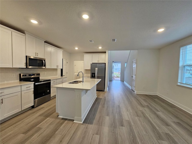 kitchen featuring appliances with stainless steel finishes, a kitchen island with sink, sink, and white cabinets