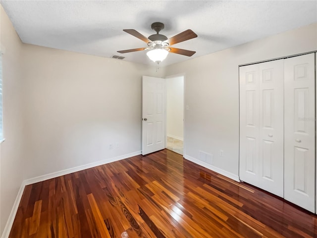 unfurnished bedroom featuring dark hardwood / wood-style flooring, ceiling fan, and a closet