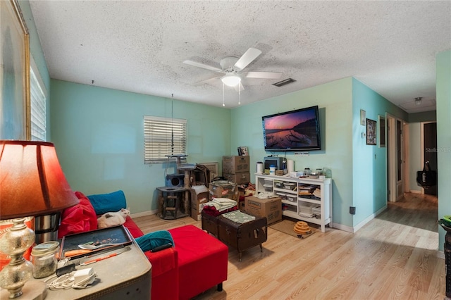 living room with ceiling fan, a textured ceiling, and light hardwood / wood-style flooring