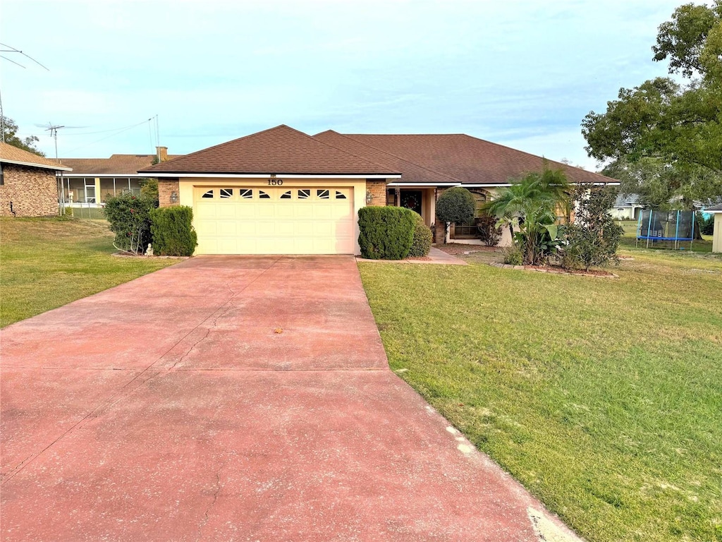 single story home featuring a trampoline, a garage, and a front lawn