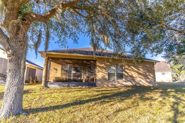 rear view of house featuring a sunroom and a lawn