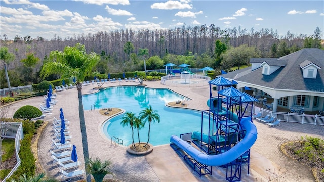 view of swimming pool with a water slide, a playground, and a patio