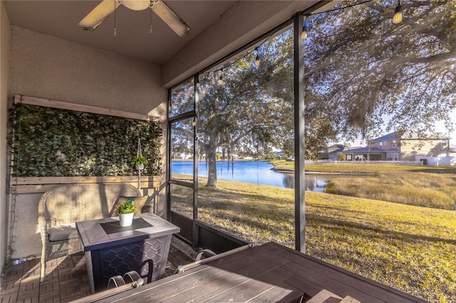 unfurnished sunroom featuring a water view and ceiling fan