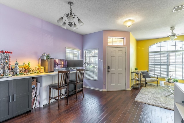 office space featuring ceiling fan with notable chandelier, dark wood-type flooring, and a textured ceiling