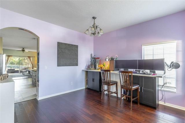 home office featuring dark hardwood / wood-style flooring, ceiling fan with notable chandelier, and a textured ceiling