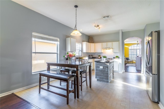 kitchen with a kitchen island, decorative light fixtures, sink, stainless steel fridge, and decorative backsplash