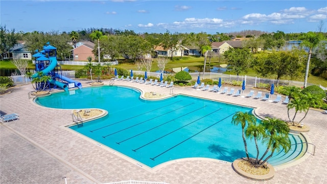 view of swimming pool with a water slide, a playground, and a patio area