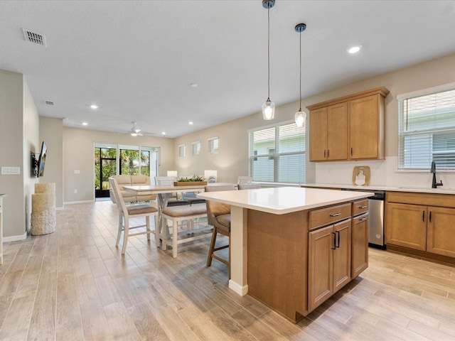 kitchen featuring a kitchen island, pendant lighting, sink, a kitchen breakfast bar, and light wood-type flooring