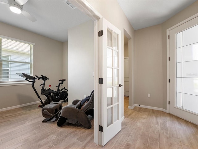 exercise area featuring french doors, ceiling fan, and light wood-type flooring