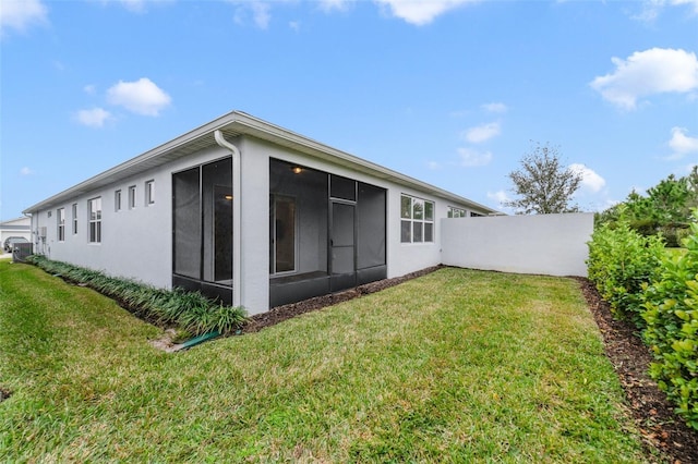 rear view of house featuring a sunroom and a yard