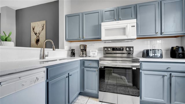 kitchen featuring sink, light tile patterned floors, white appliances, light stone countertops, and decorative backsplash