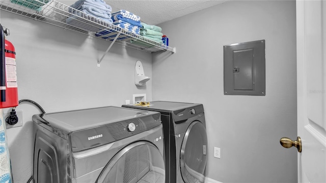 washroom featuring washing machine and dryer, electric panel, and a textured ceiling