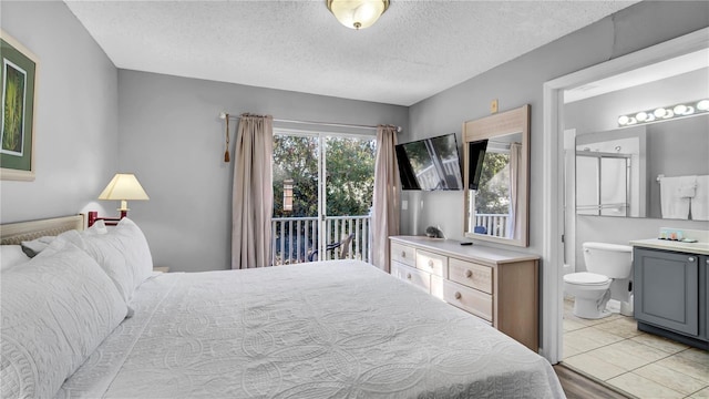 bedroom with connected bathroom, a textured ceiling, and access to outside