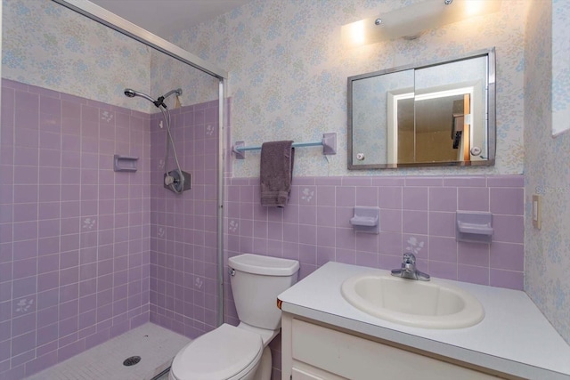 bathroom featuring vanity, a tile shower, tile walls, and toilet