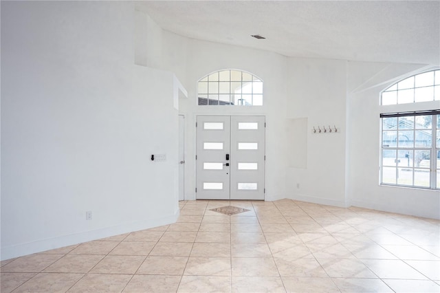 tiled foyer entrance featuring a towering ceiling and french doors