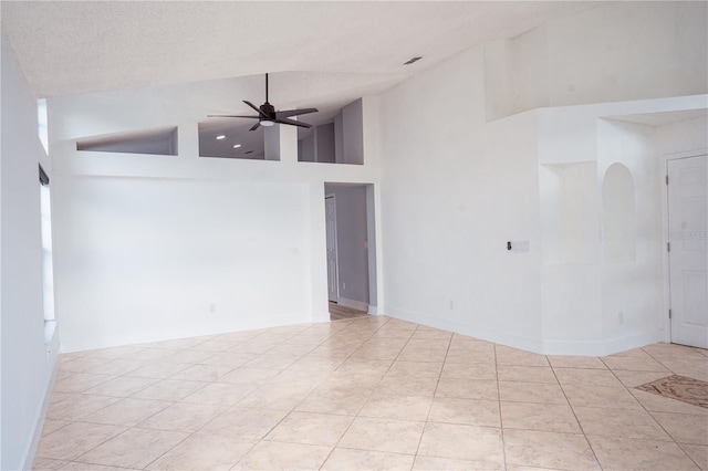 unfurnished room with light tile patterned floors, a textured ceiling, ceiling fan, and a high ceiling