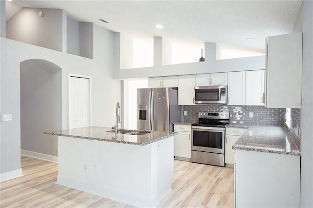 kitchen with a kitchen island, appliances with stainless steel finishes, high vaulted ceiling, sink, and white cabinets