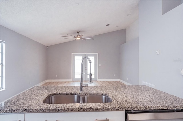 kitchen featuring lofted ceiling, sink, white cabinetry, and a healthy amount of sunlight