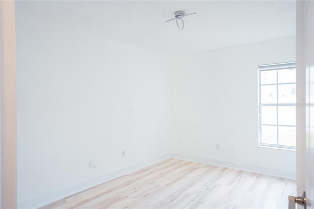 empty room featuring plenty of natural light, a textured ceiling, and light wood-type flooring