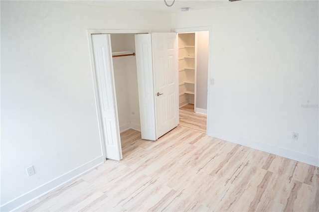 unfurnished bedroom featuring a spacious closet, light wood-type flooring, and a closet