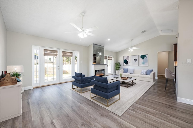 living room with hardwood / wood-style flooring, a fireplace, french doors, and vaulted ceiling