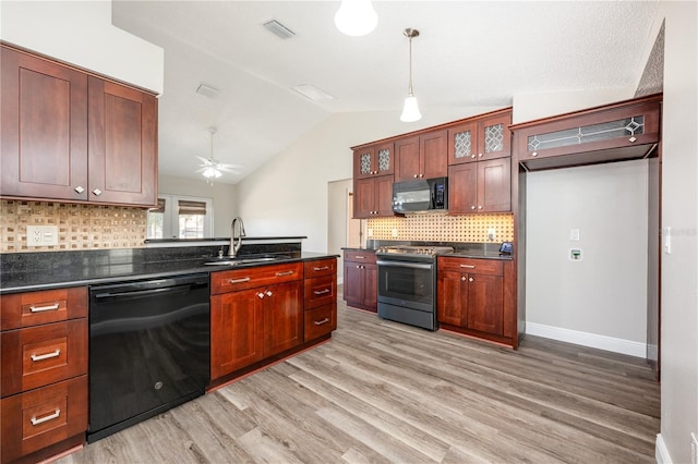 kitchen featuring sink, decorative light fixtures, vaulted ceiling, light hardwood / wood-style floors, and black appliances