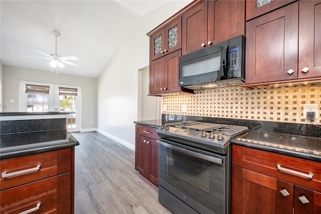 kitchen featuring lofted ceiling, light hardwood / wood-style flooring, stainless steel gas stove, tasteful backsplash, and dark stone counters