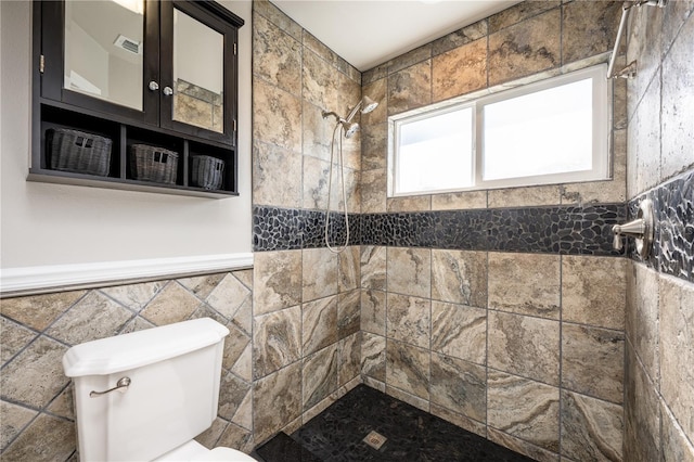 bathroom featuring a tile shower, tile walls, and toilet