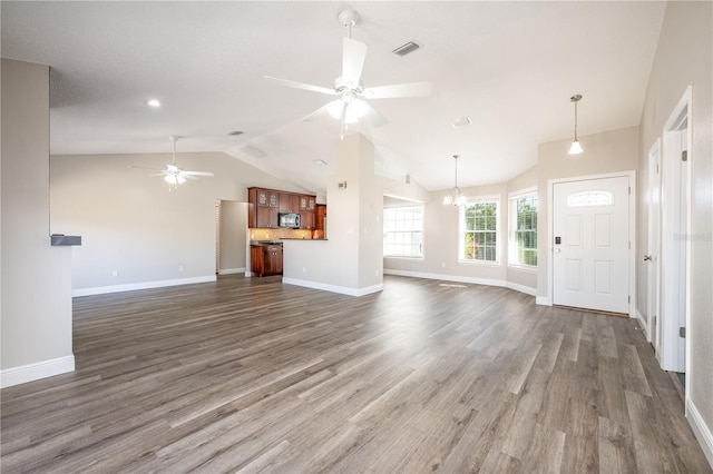 unfurnished living room with dark hardwood / wood-style flooring, ceiling fan with notable chandelier, and vaulted ceiling