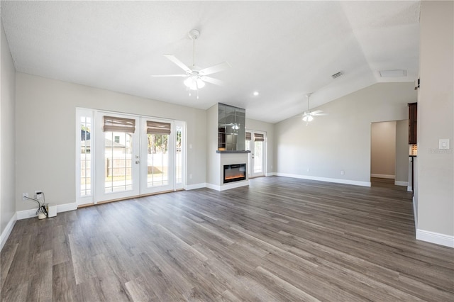 unfurnished living room featuring french doors, a large fireplace, dark hardwood / wood-style floors, and ceiling fan