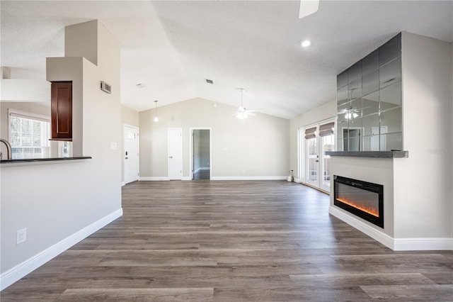 unfurnished living room featuring lofted ceiling, a healthy amount of sunlight, hardwood / wood-style floors, and ceiling fan