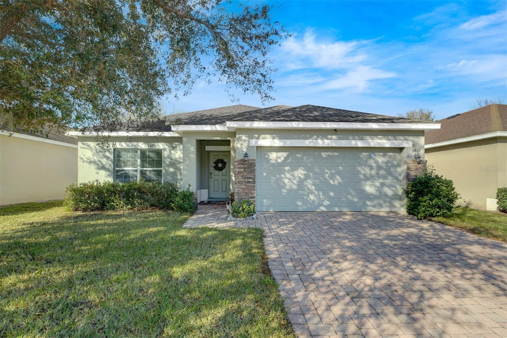 single story home with a garage and a front lawn