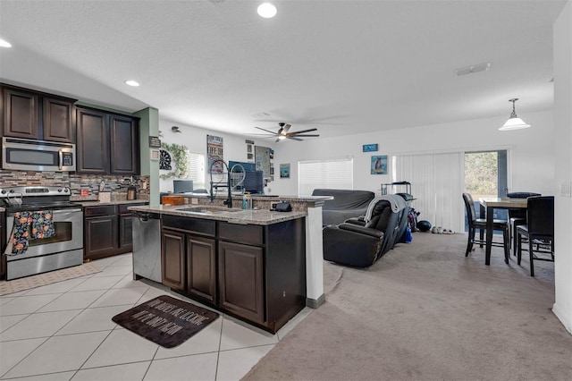 kitchen featuring an island with sink, appliances with stainless steel finishes, sink, and dark brown cabinetry