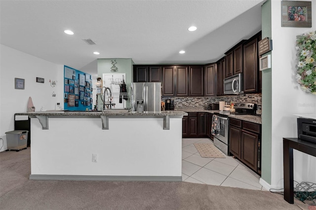 kitchen with stainless steel appliances, an island with sink, a breakfast bar, and light tile patterned flooring