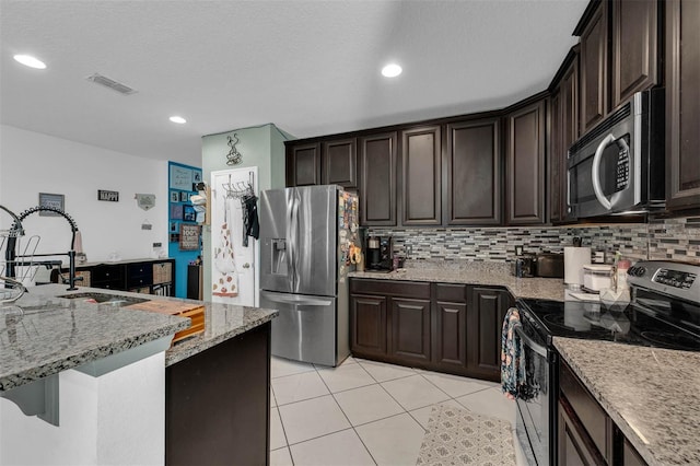 kitchen featuring light stone counters, dark brown cabinetry, stainless steel appliances, and sink