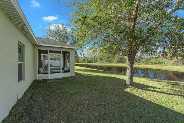 view of yard with a sunroom and a water view